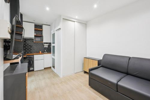 een woonkamer met een zwarte bank en een keuken bij Beautiful renovated studio metro in Levallois-Perret