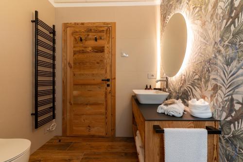 a bathroom with a wooden door and a sink at Fai le Coccole in Fai della Paganella