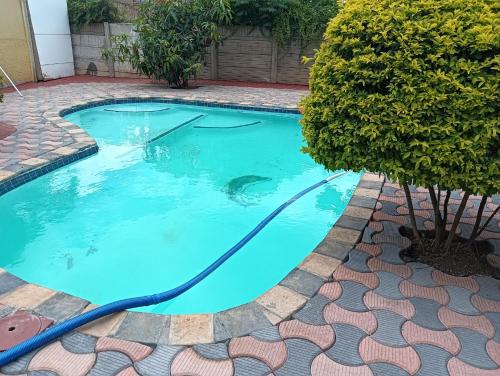 a swimming pool with a hose in a yard at Desita La' Guesthouse in Rustenburg