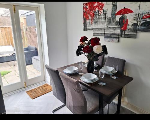 a dining room table with a vase of flowers on it at Bedlington 3 bed house in Bedlington