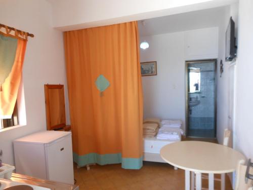an orange curtain in a room with a table at Gyrouli Studios in Astypalaia