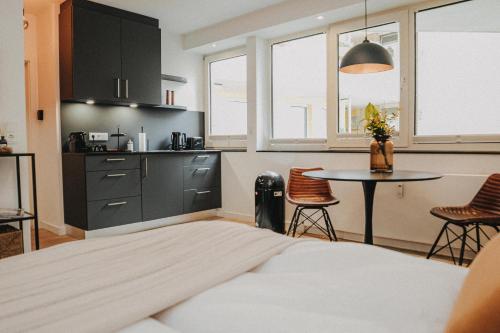 ein Schlafzimmer mit Bett und Tisch und eine Küche in der Unterkunft DOWNTOWN Apartment mit Luxusbad am Hafen nur 5 Minuten zu Fuß in die Innenstadt und zum Bahnhof! in Oldenburg