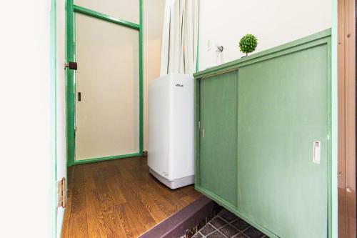 a room with a green wall and a refrigerator at Nagasaki Night View Stay 長崎絶景ステイ - Lotus長崎 in Nagasaki
