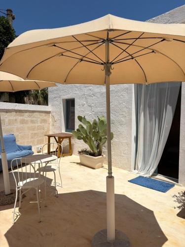 a large umbrella on a patio with a table and chairs at Masseria Verbena Agriturismo in Monopoli
