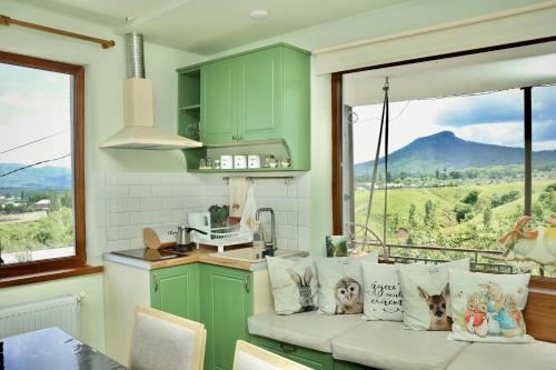 a kitchen with green cabinets and a bench with pillows at Tesaran Stepanavan Guest House, Apart Hotel in Stepʼanavan