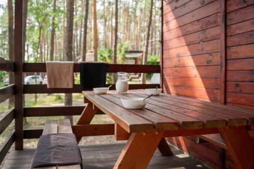 a wooden picnic table with bowls on top of it at Domki-Temar Kompleks Wypoczynkowy in Dąbie