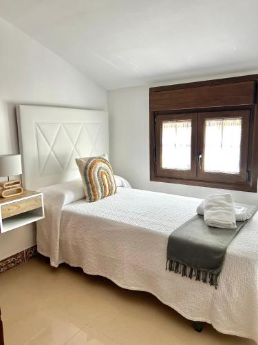 a white bedroom with two beds and a window at CENTER APARTMENT Mazagón in Mazagón