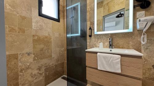 a bathroom with a shower and a sink and a mirror at Hôtel La Pinède in Soulac-sur-Mer