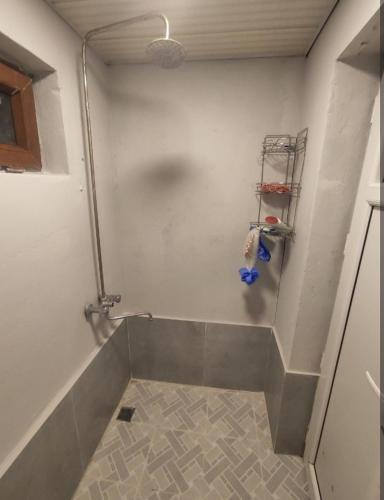 a bathroom with a shower and a tile floor at Ulduzlu ev in Sheki