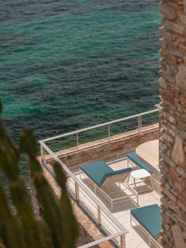 a balcony with chairs and the ocean in the background at Hôtel Les Roches - Relais & Châteaux in Le Lavandou