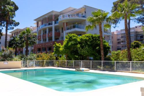 a swimming pool in front of a building with palm trees at Studio contemporain Blue lagoon 3 étoiles in Hyères