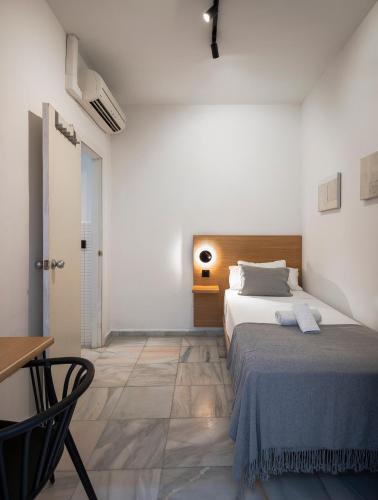 a bedroom with a bed and a table and a chair at La Central Sevilla in Seville