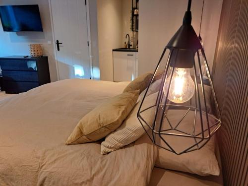 a lamp hanging over a bed with pillows at B&B Buitengewoon in Fochteloo