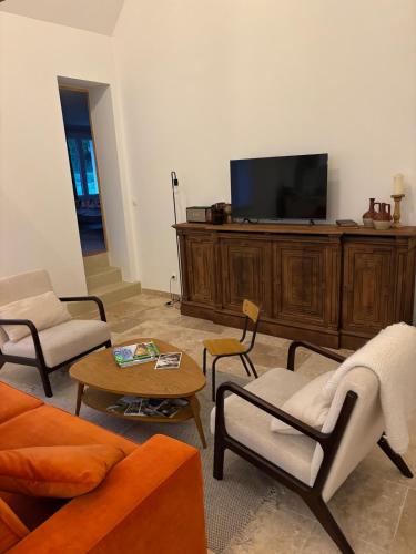 ein Wohnzimmer mit einem TV auf einem hölzernen Entertainment-Center in der Unterkunft Gîte Le Guet du Roy in Boismont