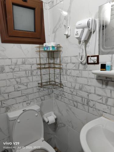 a white bathroom with a toilet and a sink at JJ Guesthouse in Aswan