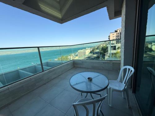 a table and chairs on a balcony with a view of the ocean at the royal lake views in Tiberias
