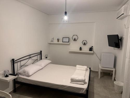 a white bedroom with a bed and a tv at GuccisCozyStudio in Artemida