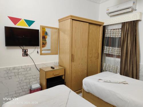 a hotel room with two beds and a tv at JJ Guesthouse in Aswan
