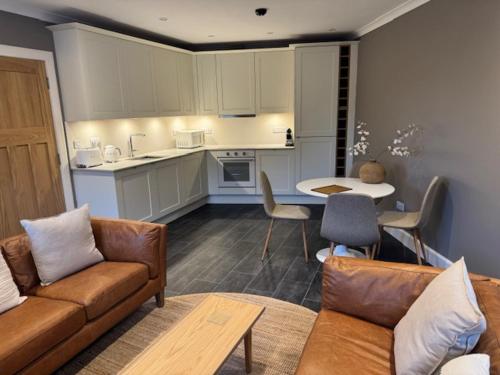 a living room with a couch and a table and a kitchen at Aaron Glen Guest Apartments in Loanhead