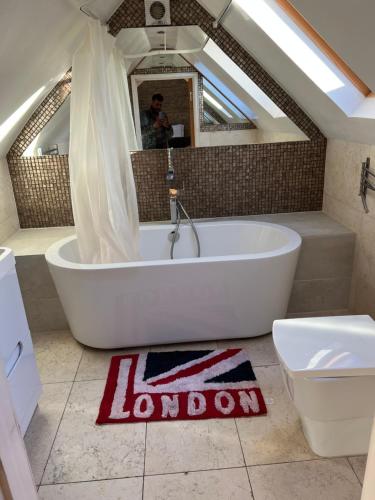 a bathroom with a tub and a toilet and a mirror at 3 x Studios Golden Manor in Hanwell