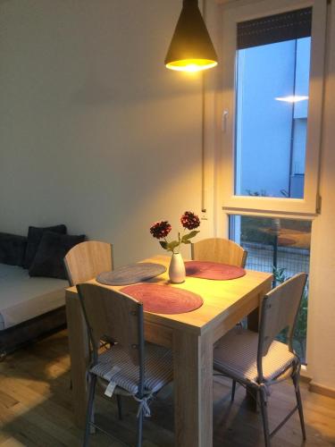 a dining room table with chairs and a vase with flowers on it at Vala Mar Apartments by Four C in Hamallë