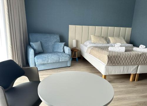 a bedroom with a bed and a chair and a table at Apartamenty Coastal Comfort Kołobrzeg in Kołobrzeg