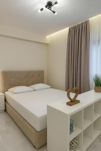 a white bedroom with a bed and a window at Studio Lumo in Nea Moudania