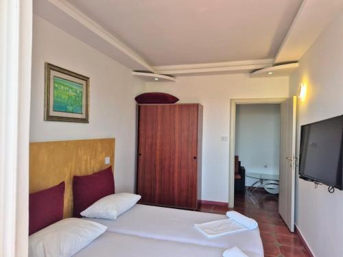 a bedroom with a bed with a television and a door at Apartments Yll in Ulcinj