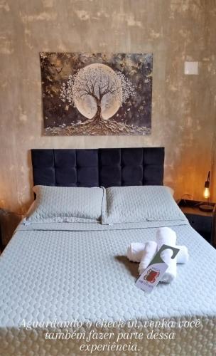 a bedroom with a bed with a tree painting on the wall at Pousada Portas da Lua in Catas Altas