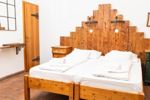 a bed with a large wooden headboard in a room at Régi Posta Hotel és Étterem in Debrecen