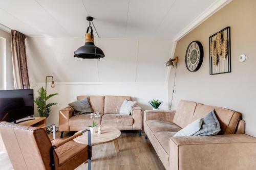 a living room with two couches and a tv at Bonte Vliegenvanger in Zwiggelte