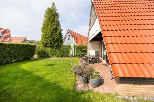 a backyard with an umbrella and a lawn at Bonte Vliegenvanger in Zwiggelte