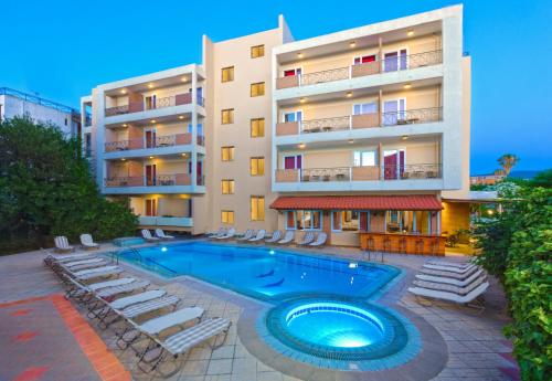 an apartment building with a swimming pool and lounge chairs at Pavlos Hotel in Kos