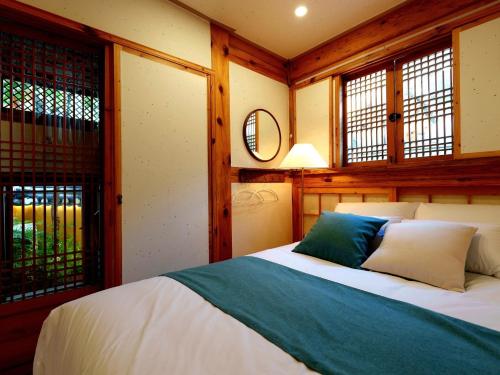 a bedroom with a bed in a room with windows at #오픈할인# 경복궁역 도보 4분#한옥#전통체험#경복궁,인사동,북촌,서촌,광화문,명동, 동대문 바로 옆#짐보관# 9인#호텔침구#각방에어컨#무료와이파이#세탁건조기#교통최고 in Seoul