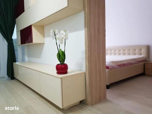 een rode vaas met witte bloemen op een tafel in een slaapkamer bij City Rest Apartment in Oradea