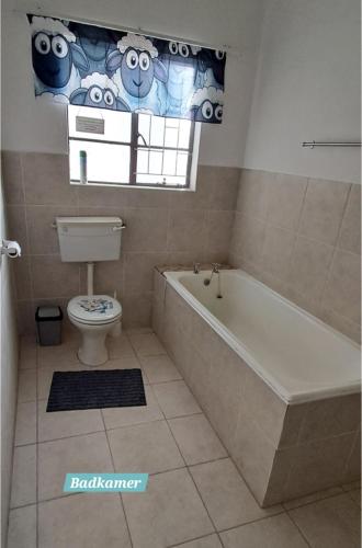 a bathroom with a tub and a toilet and a window at Papkuilsvlei Selfsorg Plaashuis in Muishondfontein