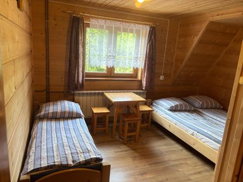 zwei Betten in einem Zimmer mit Tisch und Fenster in der Unterkunft Ludwina Żegleń Pokoje Gościnne in Małe Ciche
