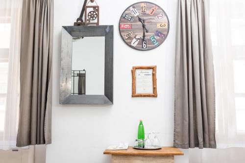 a wall with two mirrors and a clock and a table at Régi Posta Hotel és Étterem in Debrecen