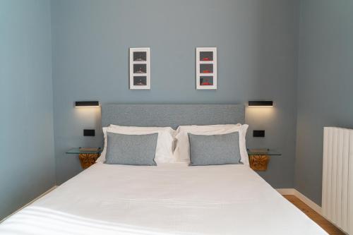 a bedroom with a white bed with three pictures on the wall at Deluxe Spaccanapoli in Naples