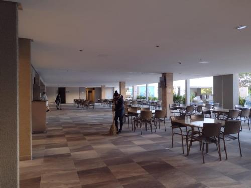 a person standing in a room with tables and chairs at Park Veredas Flat Service Rio Quente - GO Apto 416 in Rio Quente