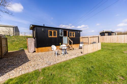 a small black house with a picnic table in a yard at Bluebell Hut in Bristol