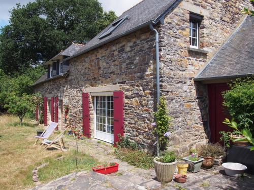a stone house with red doors and a yard at La Sorcière et le Korrigan in Paimpont