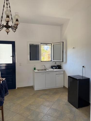 a white kitchen with a sink and a window at Tinos beauty village in Kalloní