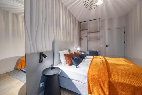a bedroom with a large bed with an orange blanket at Apartamenty Baltic Waves - visitopl in Międzyzdroje