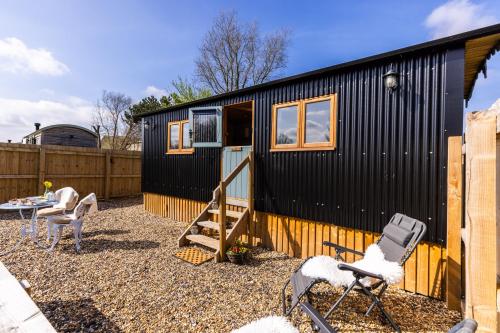 a black tiny house with a table and chairs at Bluebell Hut in Bristol