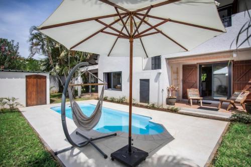 an umbrella and a chair next to a swimming pool at Villa Céleste - 4 Bedrooms in Central Tamarin in Tamarin