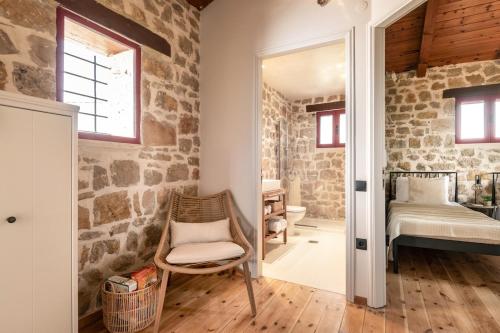 a room with stone walls and a chair and a bedroom at Geracasa Stone Villa in Méson Yerakaríon