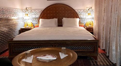 a bedroom with a large bed with a wooden headboard at Palais AL Firdaous in Fès