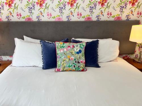 a white bed with pillows and a floral wallpaper at Crieff Armoury in Crieff
