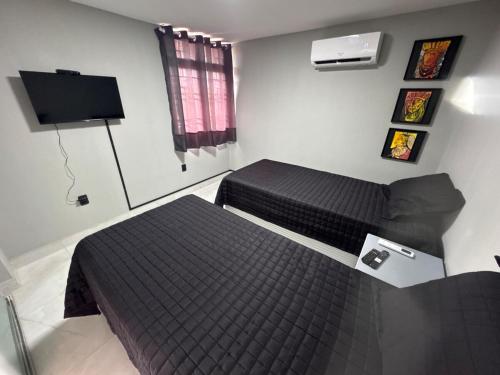 a bedroom with two beds and a flat screen tv at Charmoso apartamento no Centro de Patos PB in Patos